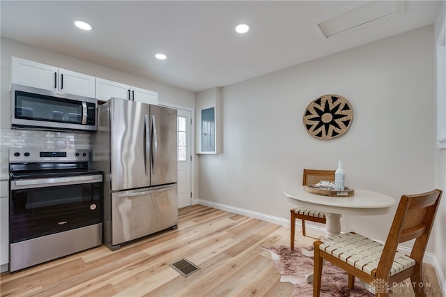 kitchen featuring stainless steel appliances, visible vents, white cabinets, light wood-type flooring, and decorative backsplash