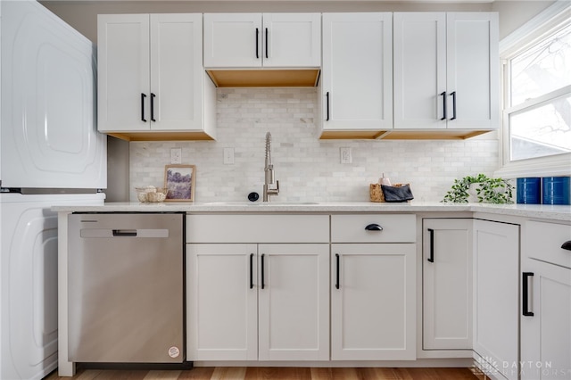 kitchen with light countertops, stainless steel dishwasher, a sink, and white cabinetry