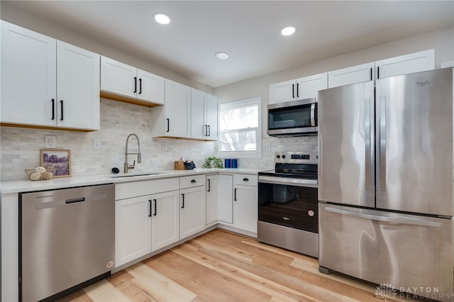 kitchen with light countertops, appliances with stainless steel finishes, a sink, and white cabinets