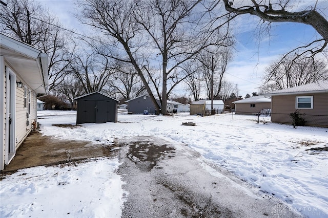 yard covered in snow featuring a storage shed and an outdoor structure