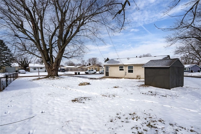 yard covered in snow featuring a garage, a storage unit, and an outdoor structure