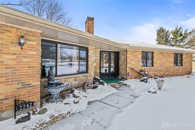 exterior space featuring stone siding, brick siding, and a chimney