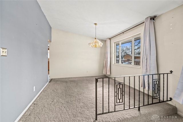 spare room featuring carpet, a notable chandelier, stairway, and baseboards