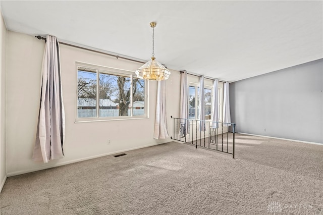 carpeted empty room with a chandelier, baseboards, visible vents, and a healthy amount of sunlight