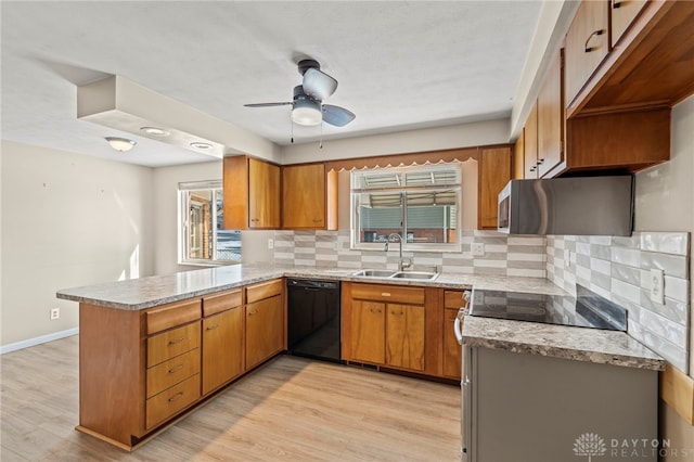 kitchen with black dishwasher, light wood-style flooring, brown cabinetry, a sink, and a peninsula