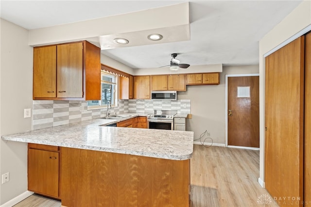 kitchen featuring appliances with stainless steel finishes, brown cabinetry, a peninsula, and decorative backsplash