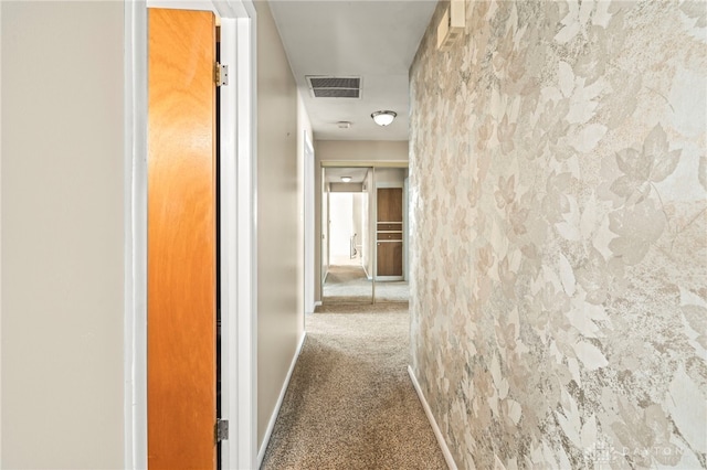 corridor with carpet, visible vents, and baseboards