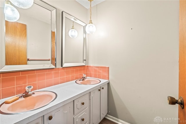 full bathroom featuring a sink, double vanity, backsplash, and baseboards