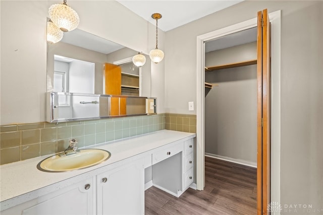 bathroom with a spacious closet, backsplash, vanity, and wood finished floors