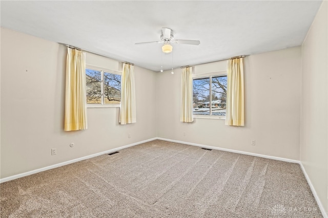 carpeted empty room with baseboards, visible vents, and ceiling fan