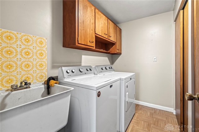 clothes washing area with cabinet space, a sink, washer and clothes dryer, and baseboards