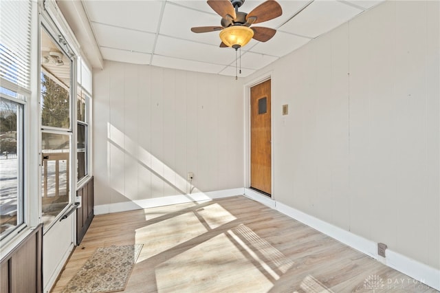 unfurnished room featuring a paneled ceiling, light wood finished floors, ceiling fan, and baseboards