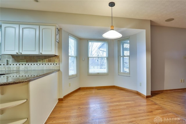 unfurnished dining area with light wood-type flooring and baseboards