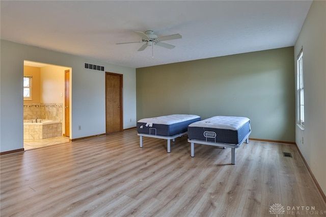 bedroom with ensuite bath, light wood-style floors, baseboards, and visible vents