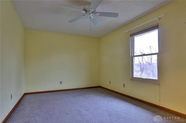 spare room featuring baseboards, a ceiling fan, and light colored carpet