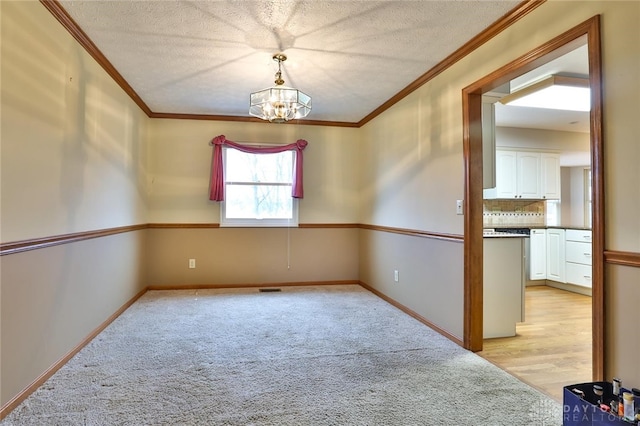 spare room featuring light colored carpet, crown molding, baseboards, and an inviting chandelier