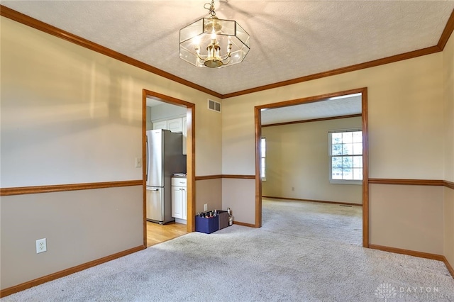 spare room with a textured ceiling, visible vents, and light colored carpet