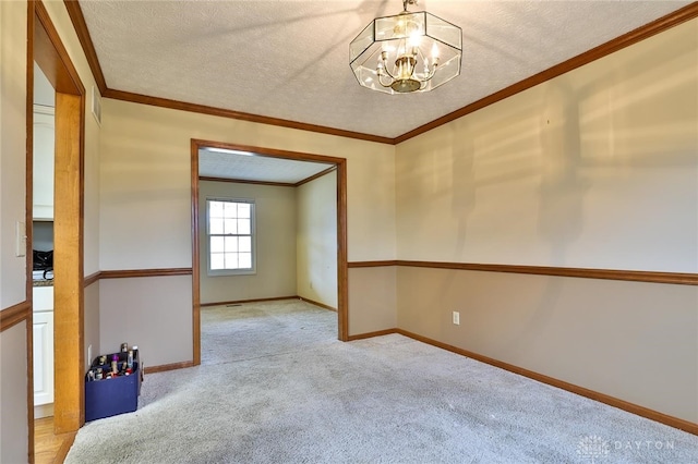 empty room with ornamental molding, light carpet, a textured ceiling, and baseboards