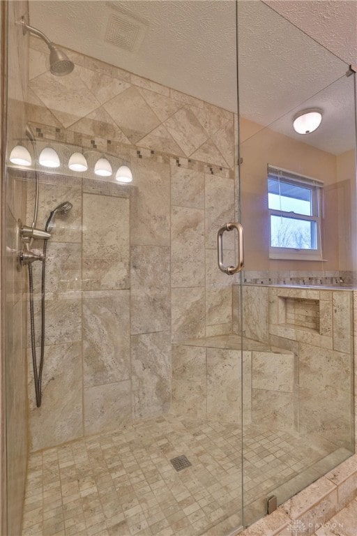 full bathroom featuring a textured ceiling and a shower stall