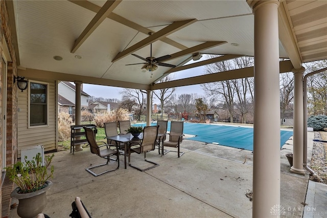 view of patio with a ceiling fan, outdoor dining space, and a covered pool