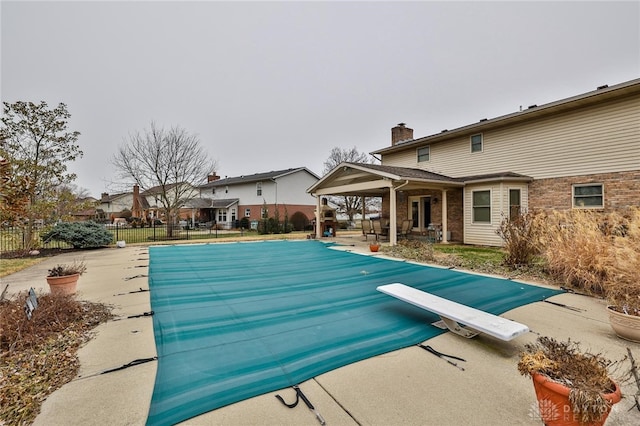 view of swimming pool featuring a fenced in pool, a patio area, fence, and a diving board