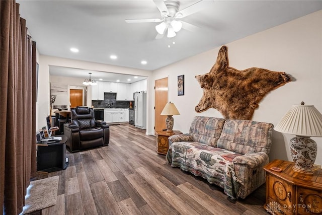 living area with recessed lighting, wood finished floors, and ceiling fan with notable chandelier