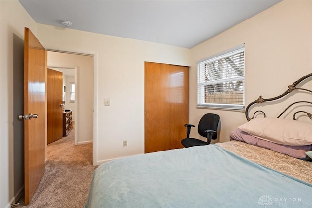 bedroom with a closet, light colored carpet, and baseboards