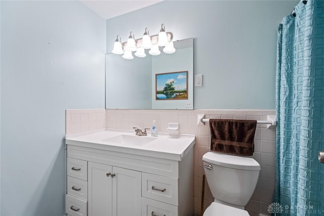 full bathroom featuring toilet, a wainscoted wall, a shower with shower curtain, vanity, and tile walls