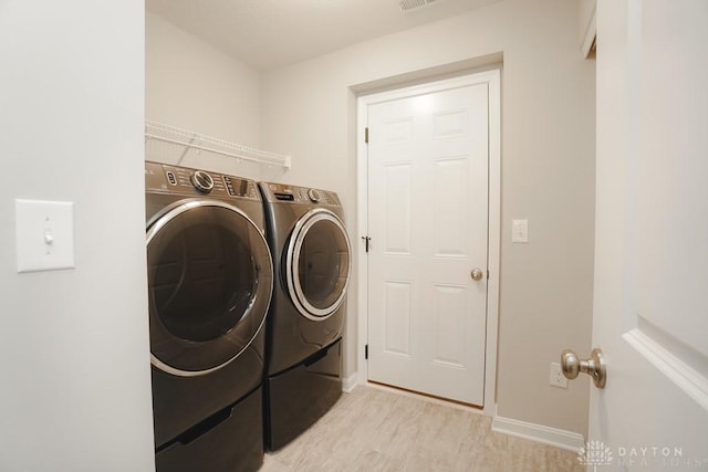 clothes washing area featuring laundry area, visible vents, baseboards, and washer and dryer