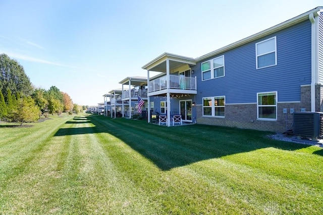 rear view of property featuring central AC, a lawn, and brick siding