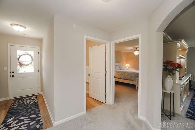 entrance foyer featuring arched walkways, light carpet, and baseboards