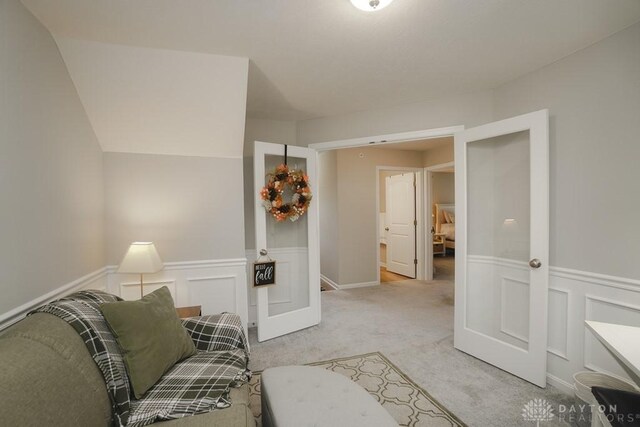 living area with wainscoting and light colored carpet