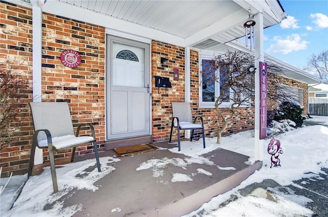 snow covered property entrance with brick siding