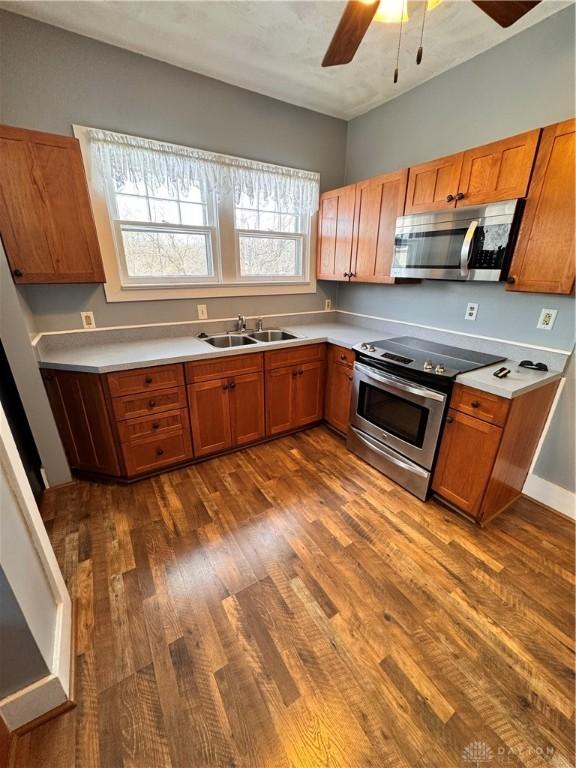 230 New Columbia Blvd, Sidney, OH 45365 - kitchen featuring brown cabinetry, appliances with stainless steel finishes, dark wood-style flooring, light countertops, and a sink