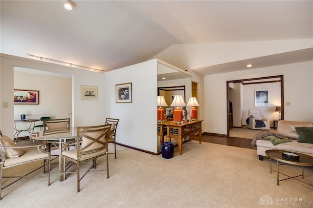 dining space featuring baseboards, vaulted ceiling, and light colored carpet