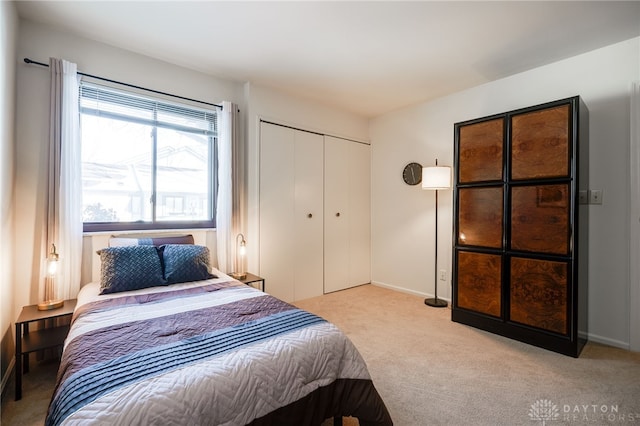 bedroom featuring baseboards, a closet, and light colored carpet