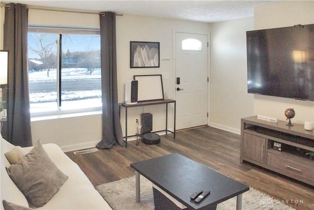 living area with dark wood-style floors, visible vents, and baseboards