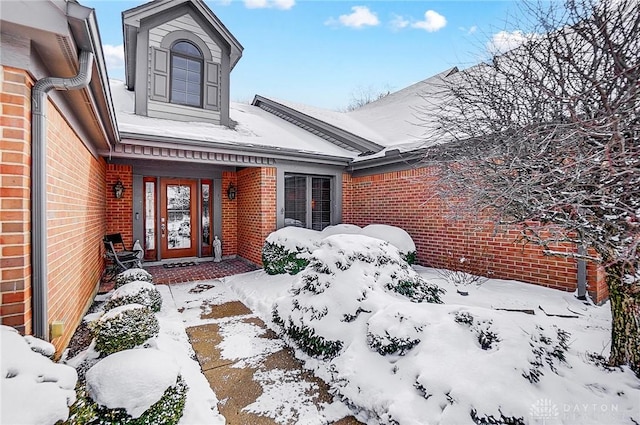 snow covered property entrance with brick siding