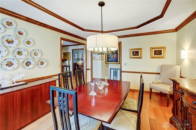 dining room featuring light wood-type flooring and crown molding