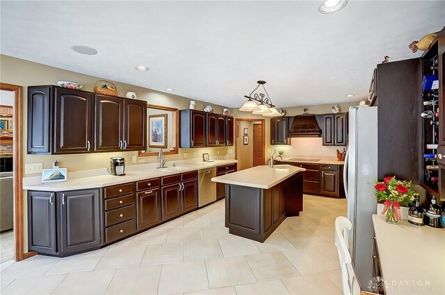 kitchen featuring freestanding refrigerator, a center island, light countertops, pendant lighting, and a sink