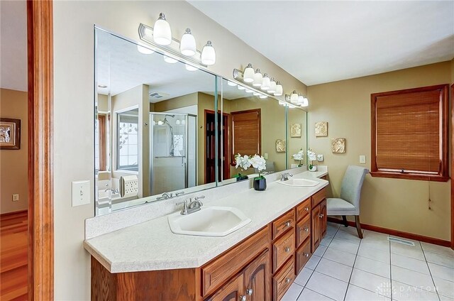 bathroom with double vanity, tile patterned floors, a sink, and a shower stall