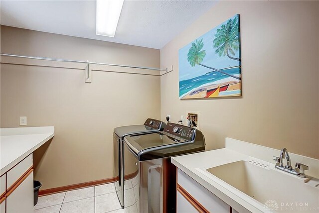 laundry area with light tile patterned floors, cabinet space, a sink, independent washer and dryer, and baseboards