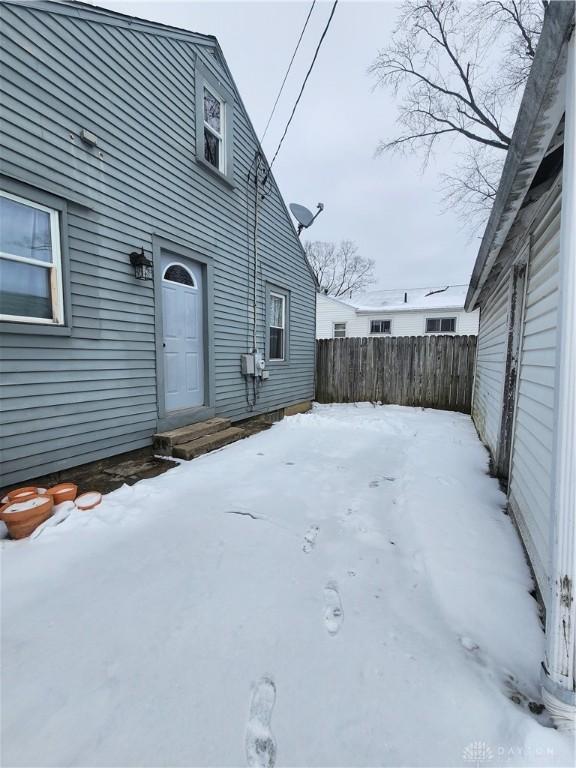 snowy yard with entry steps and fence