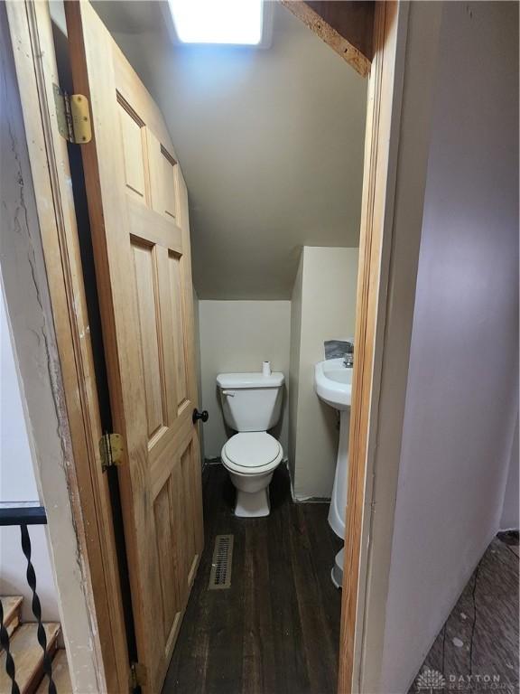 bathroom featuring toilet, visible vents, wood finished floors, and lofted ceiling