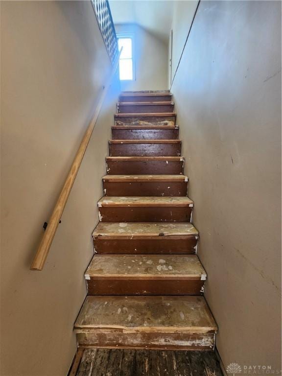 stairway featuring vaulted ceiling and wood finished floors