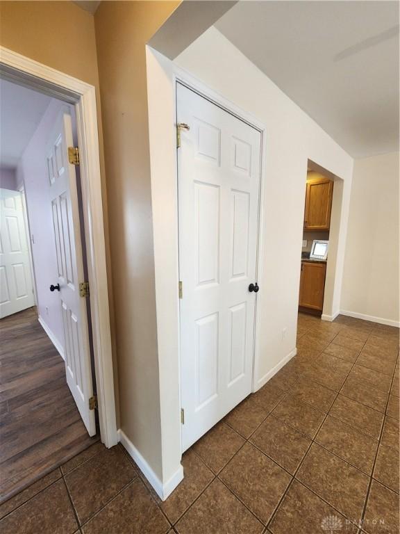 hall with dark tile patterned floors and baseboards