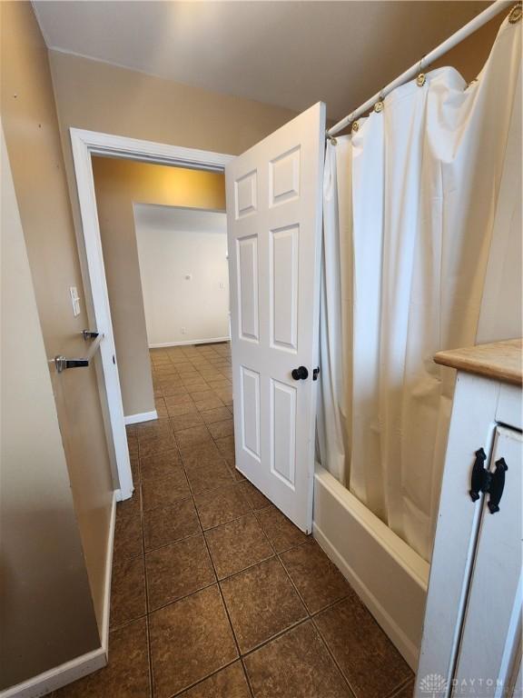 full bath with shower / tub combo, tile patterned flooring, and baseboards