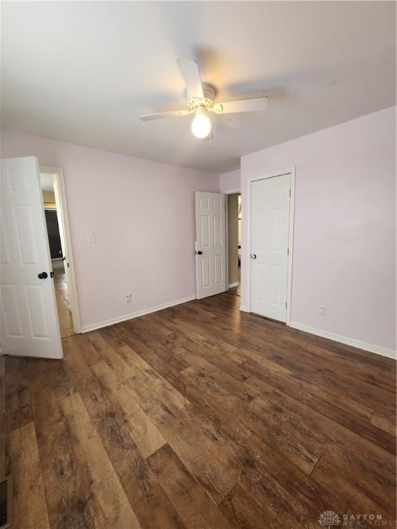 unfurnished bedroom with dark wood-style flooring, ceiling fan, and baseboards