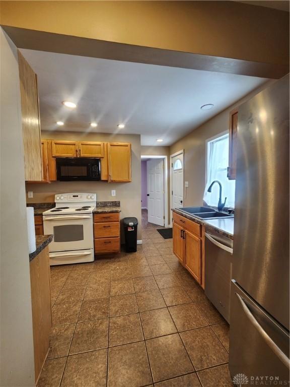 kitchen with tile patterned flooring, recessed lighting, a sink, appliances with stainless steel finishes, and dark countertops