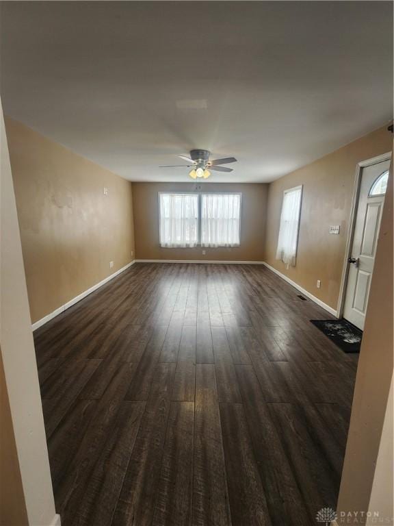 unfurnished room with dark wood-style floors, ceiling fan, and baseboards